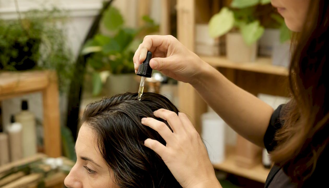 Applicazione di un siero naturale sul cuoio capelluto con delicatezza delle mani