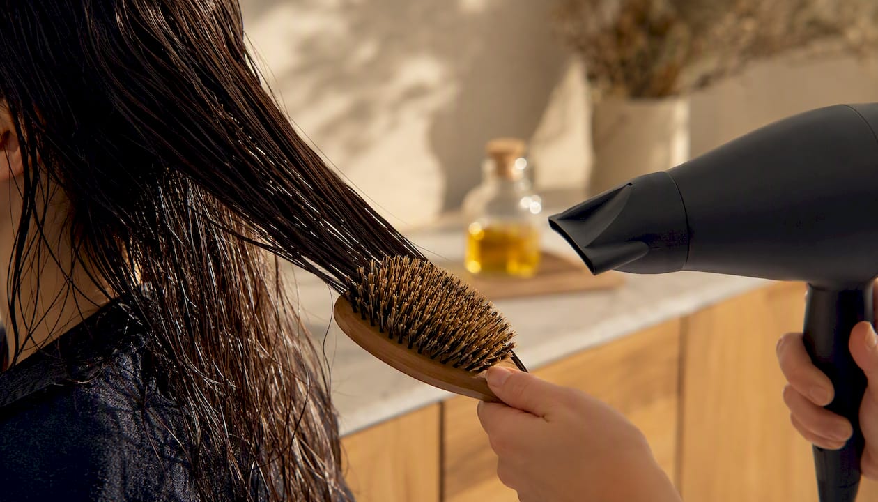 Asciugare i capelli con il phon utilizzando una spazzola con setole naturali