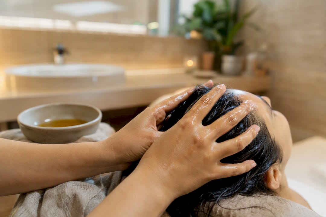 Mani che massaggiano olio caldo di Brahmi sul cuoio capelluto