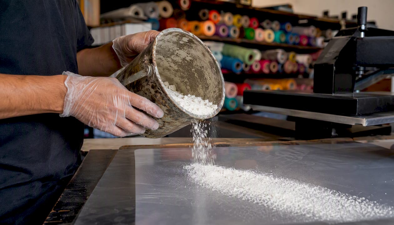 Hands scooping adhesive powder onto film