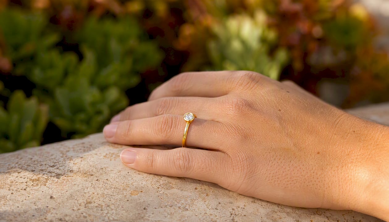 Hand wearing bezel solitaire ring low profile