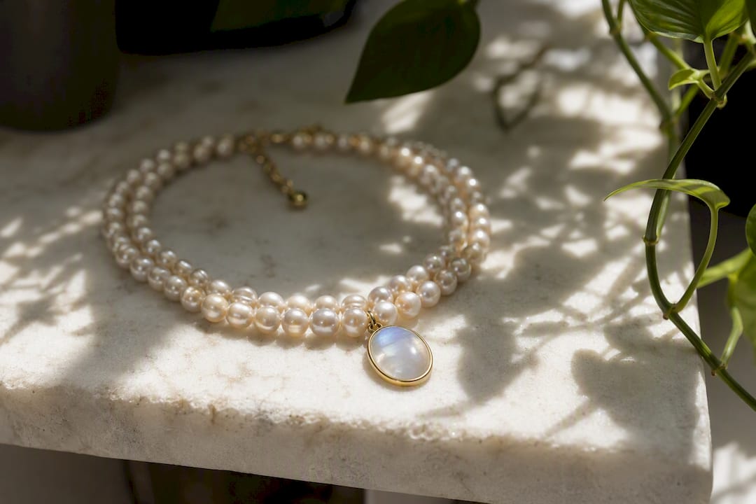 Pearl necklace and moonstone pendant on linen
