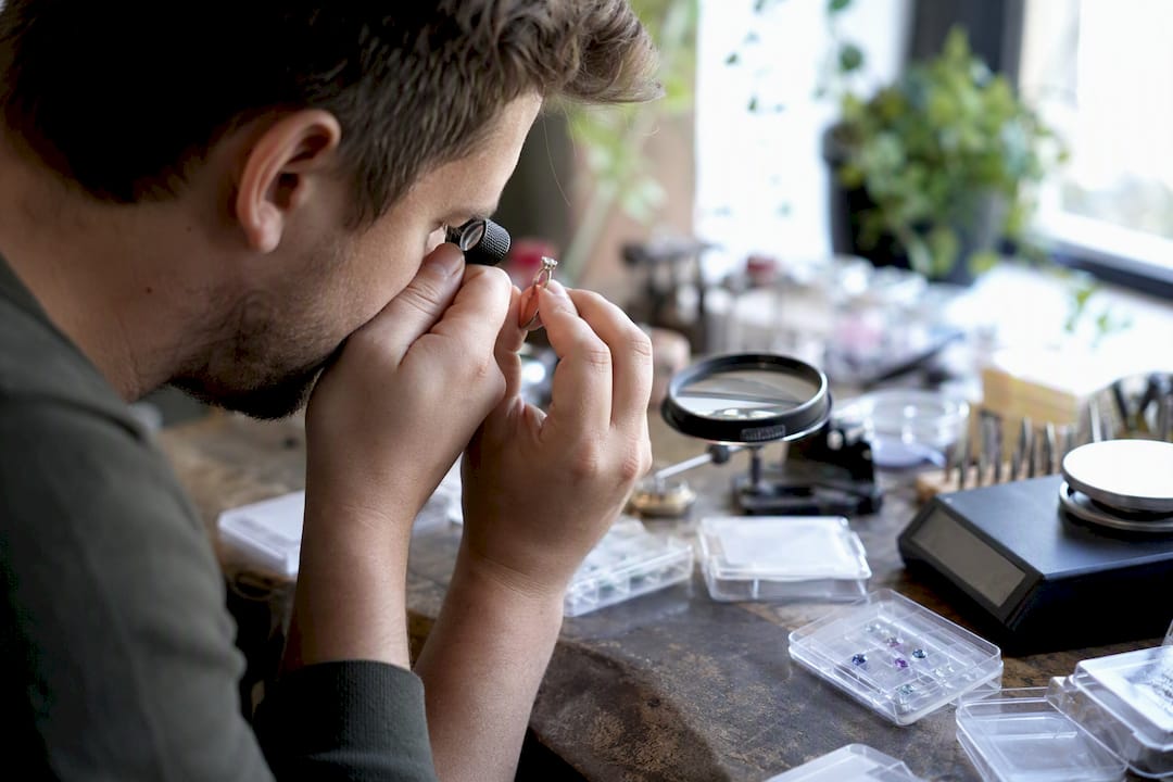 Hands appraising engagement ring with loupe