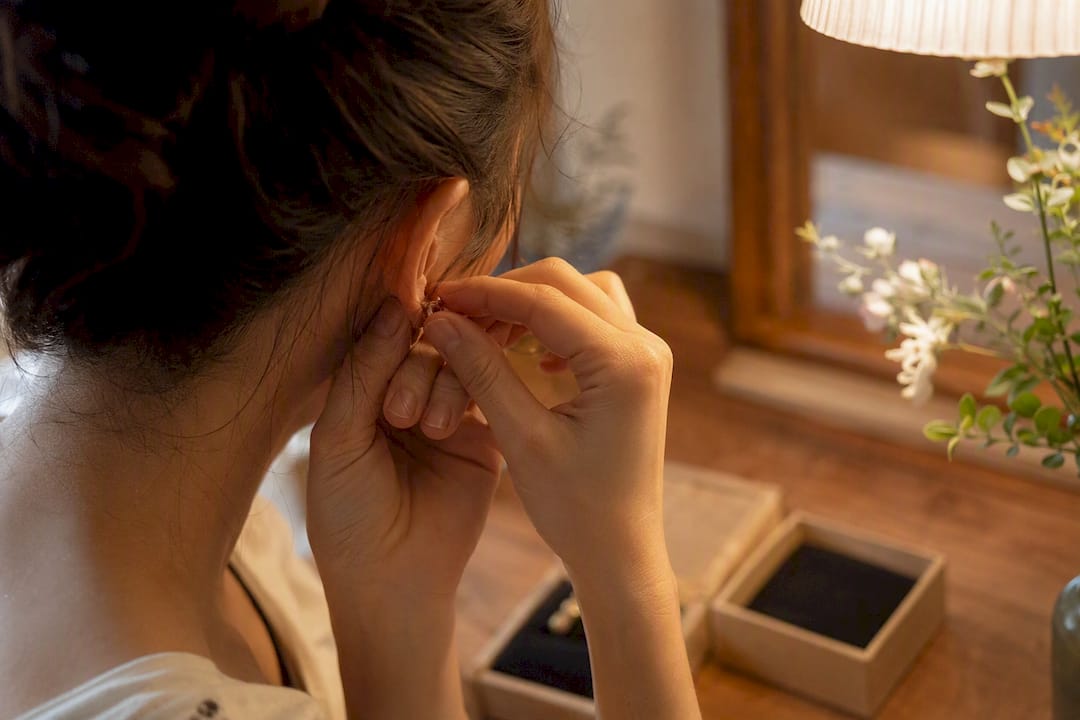 Hands screwing on earring back to post