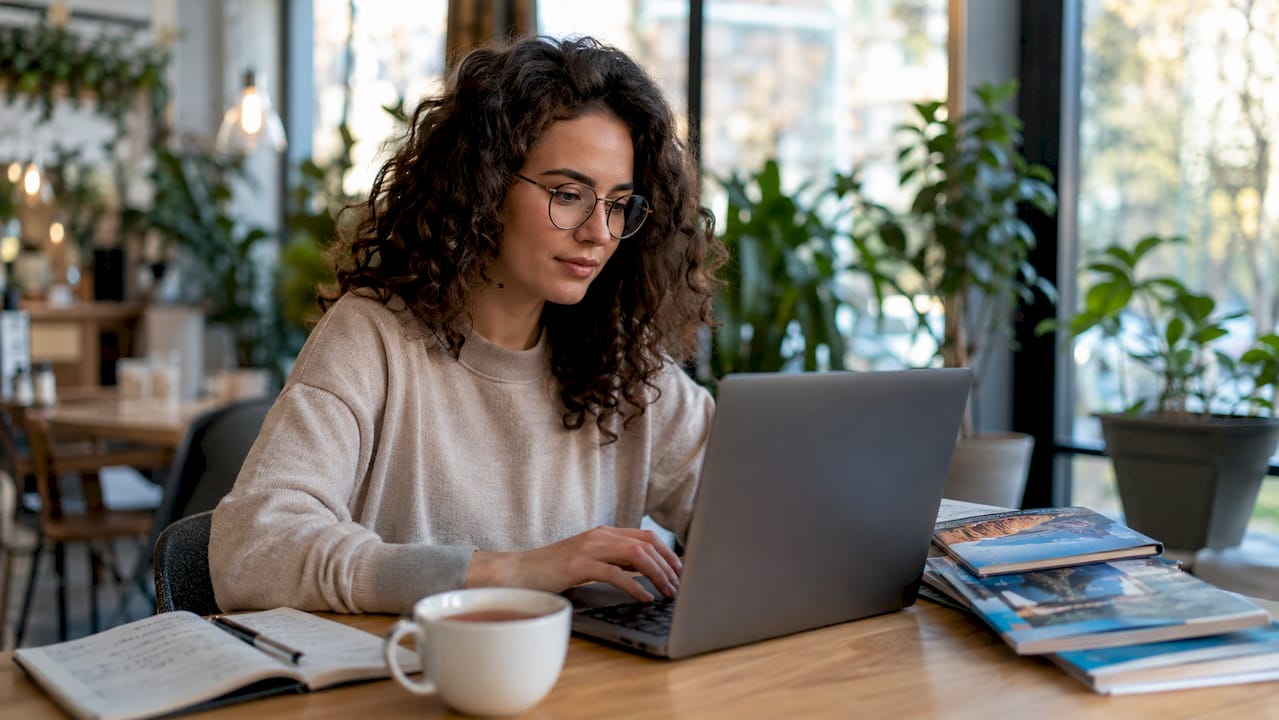Eine Frau stellt sich am Laptop ihre virtuelle Reiseroute zusammen.