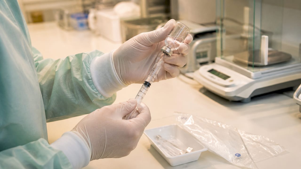 Hands preparing injectable with sterile water