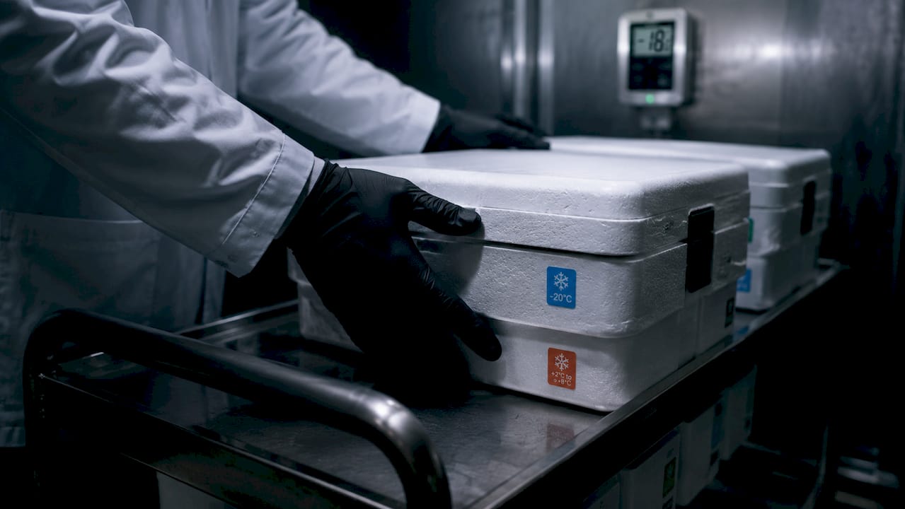 Un technicien manipule des caisses contenant des réactifs chimiques.