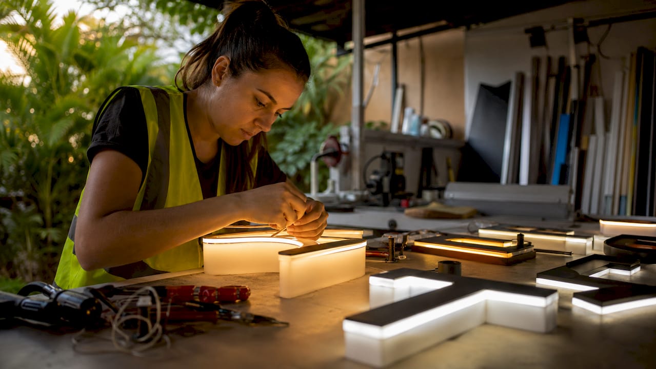 Technician assembling different illuminated sign letters in workshop