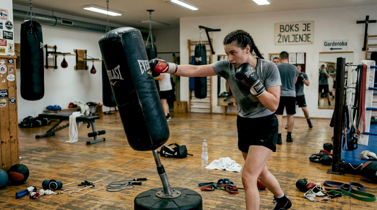 Boksar v telovadnici pilí svojo tehniko udarcev.