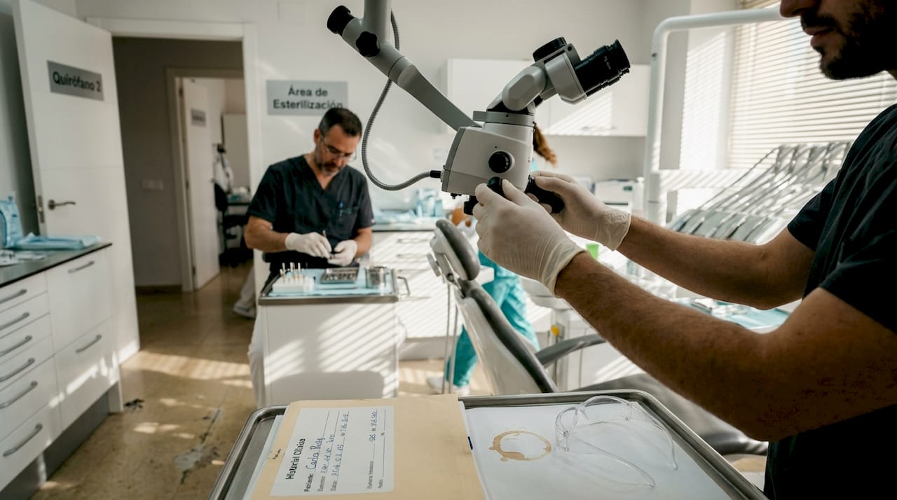 La asistente acomoda el microscopio dental sobre el sillón.