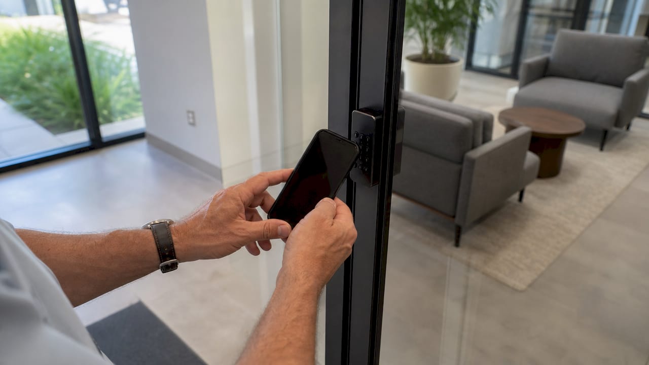 Hands holding smartphone next to keypad lock