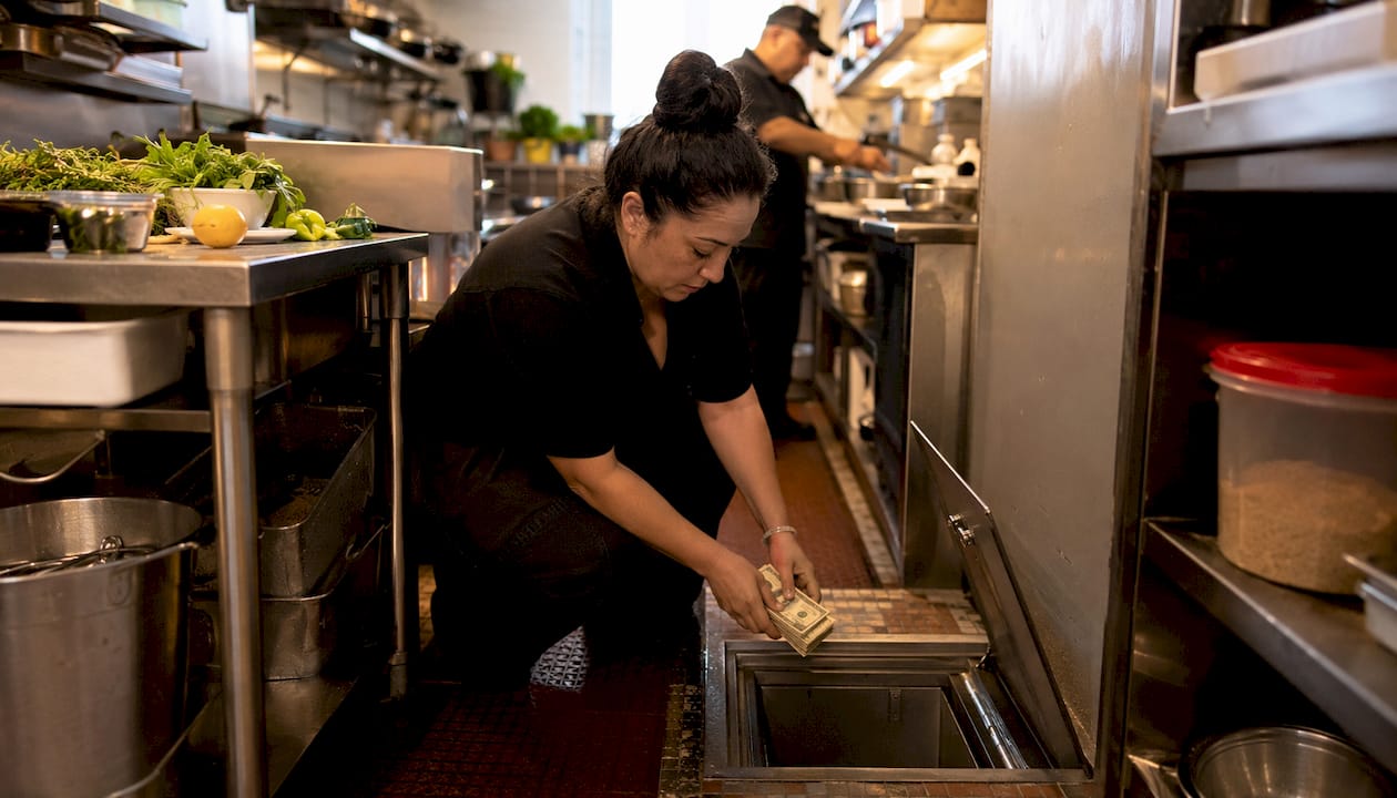 Restaurant supervisor using underfloor safe in kitchen