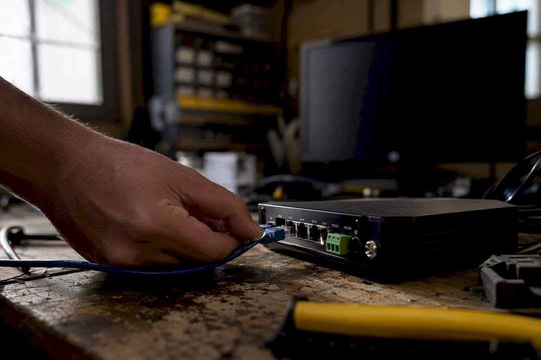 Hand holding network cable by encoder on workbench