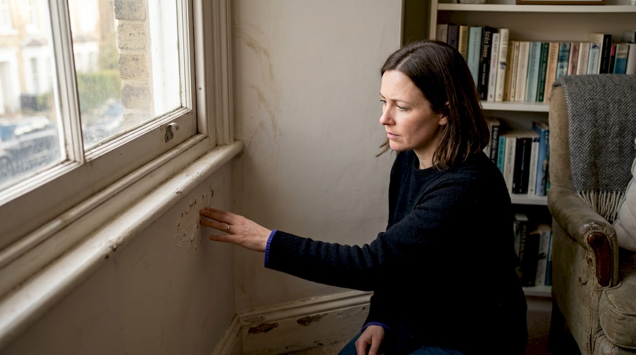 Examining bubbling interior paint near window