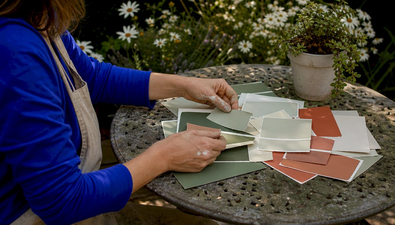 Painter comparing warm neutral paint swatches on table