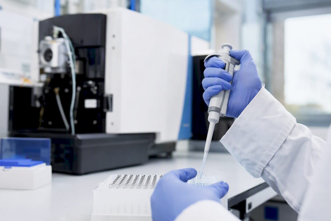 Hands pipetting sample into immunoassay test tray