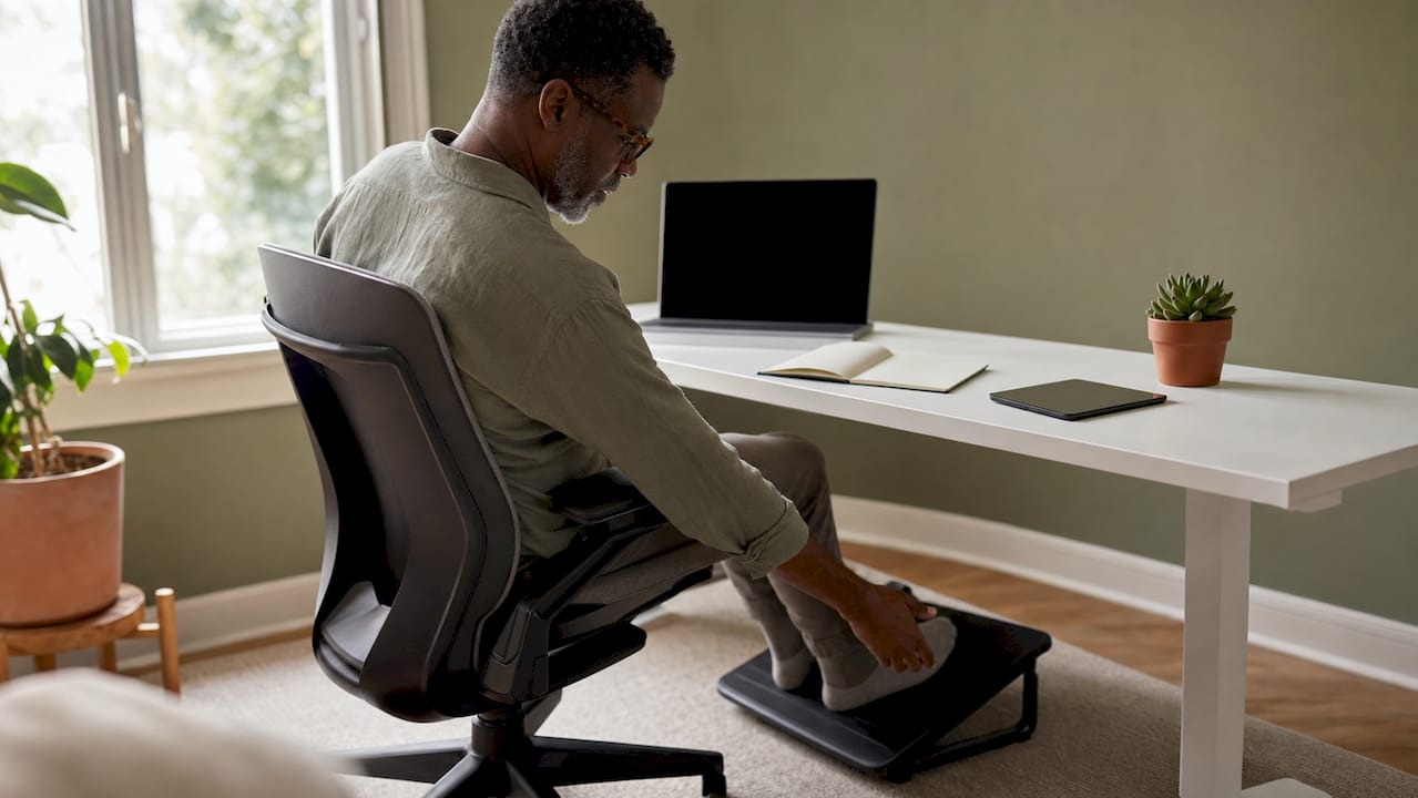 Man adjusting footrest in ergonomic office setup