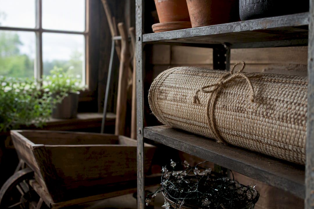 Rolled outdoor rug stored in rustic garden shed
