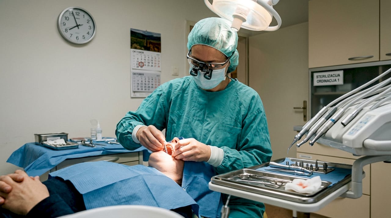 Zobozdravnik izvaja poseg vstavitve zobnega vsadka.