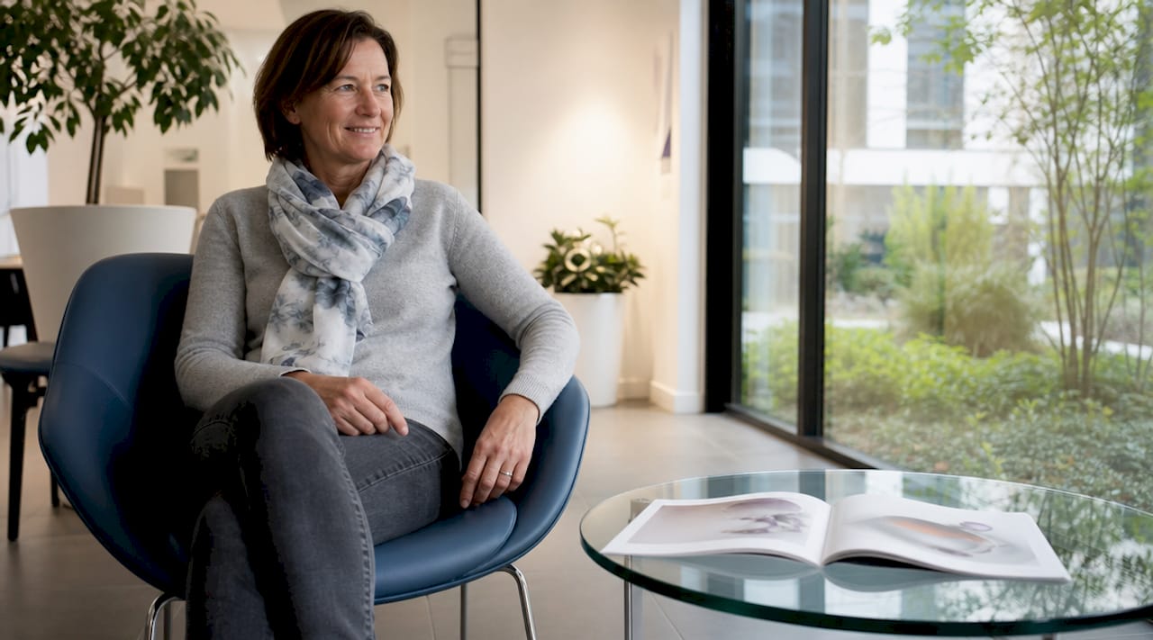 Eine Patientin sitzt im Wartebereich einer Zahnarztpraxis.