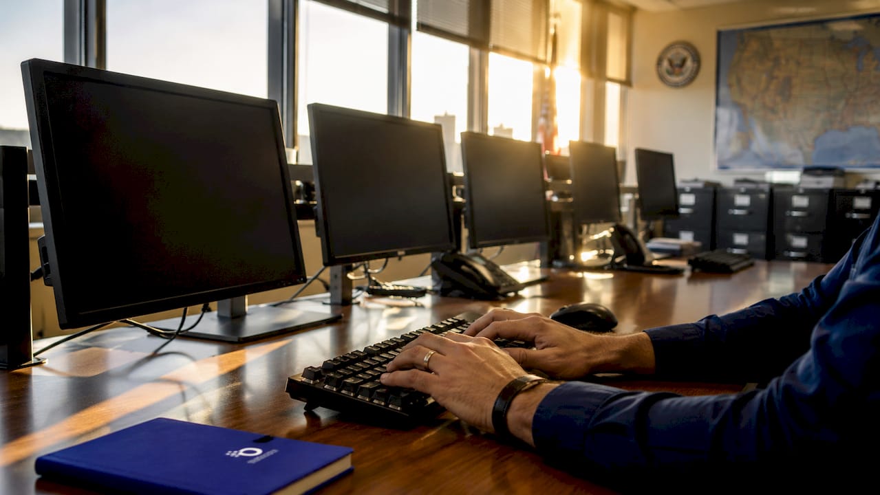 Hands typing on keyboard in intelligence analysis room