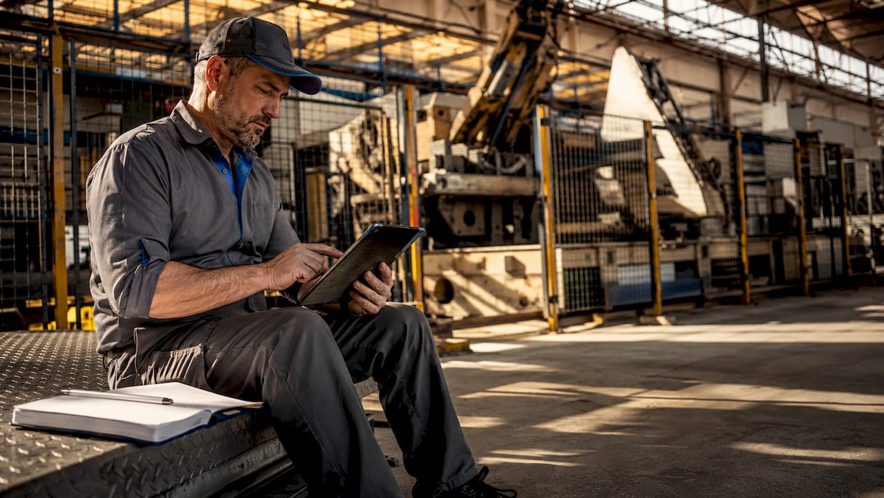 Un tecnico al lavoro in fabbrica consulta i dati su un tablet