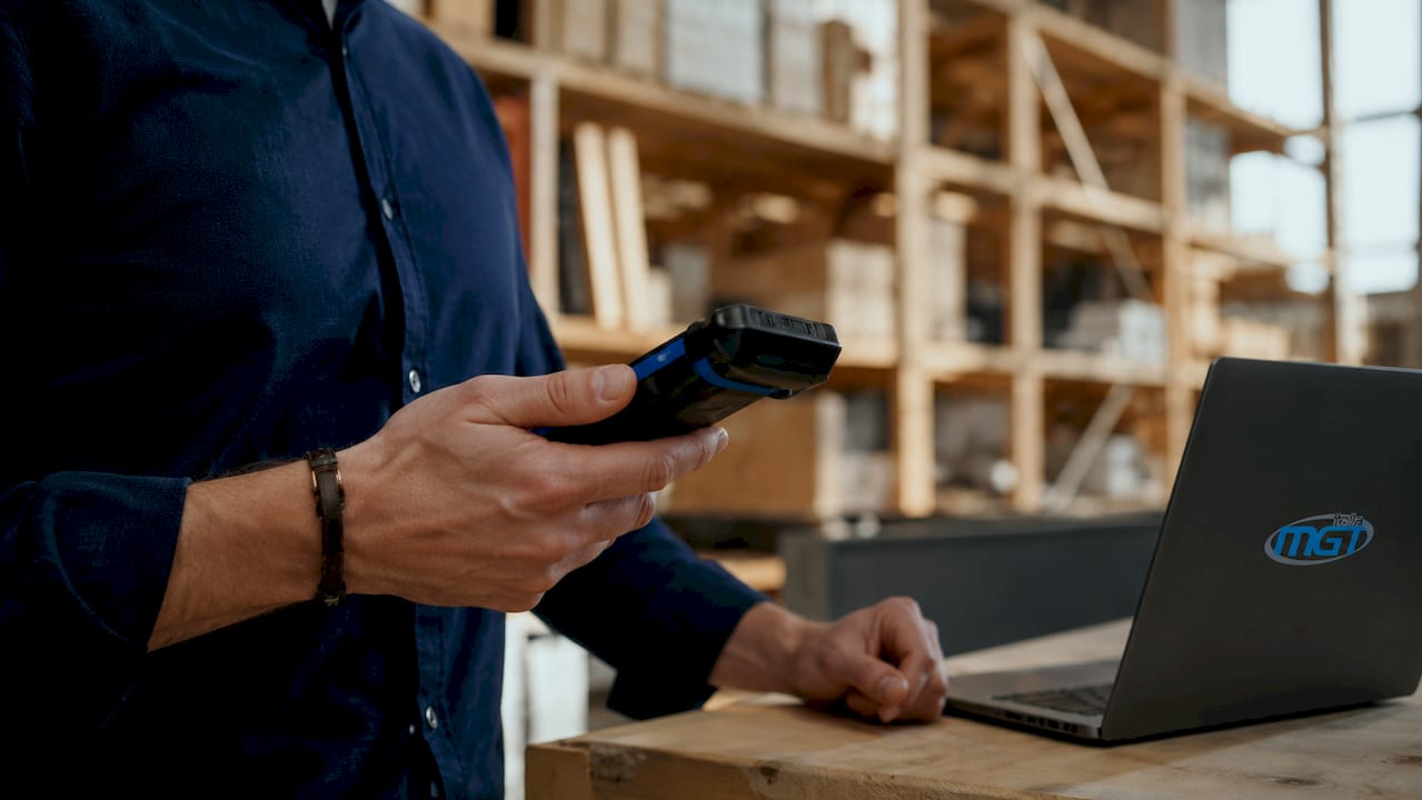 Le mani di un operatore passano uno scanner sul QR code di un macchinario industriale.