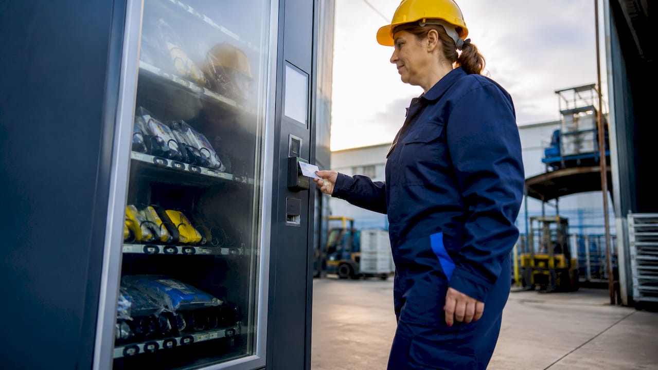 In fabbrica, un operaio si serve del distributore automatico per prelevare i dispositivi di protezione individuale.