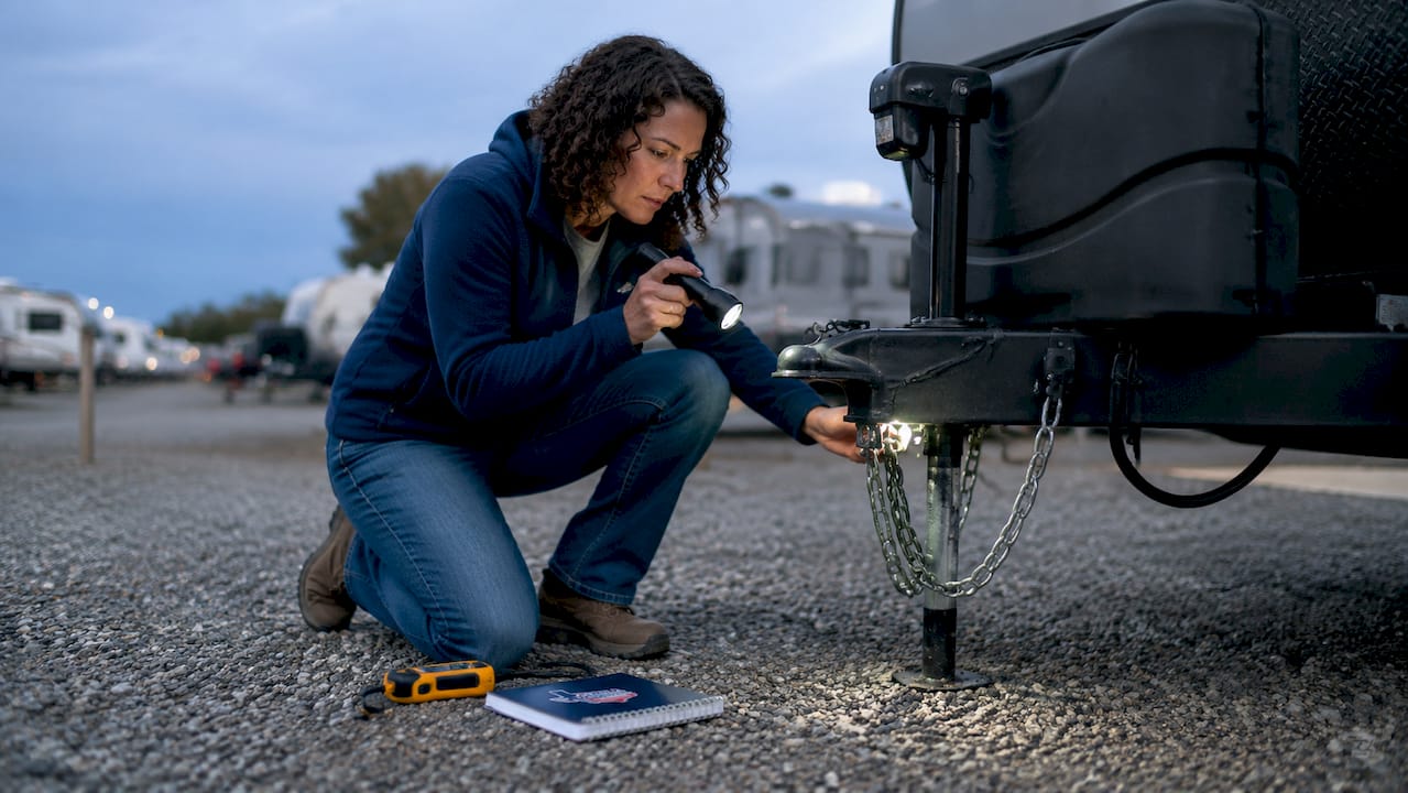Woman inspecting RV hitch and safety chains