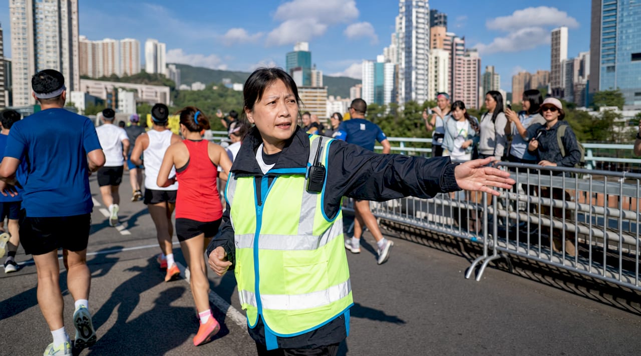 Female running marshal directing runners at race corner