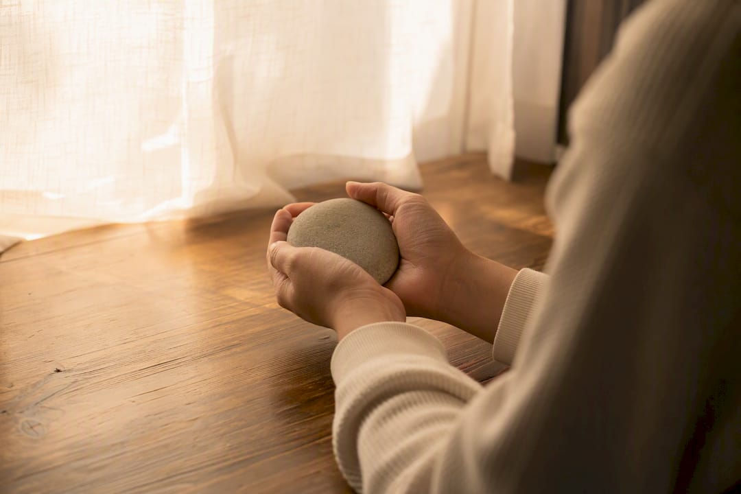 Hands holding grounding stone representing persistence