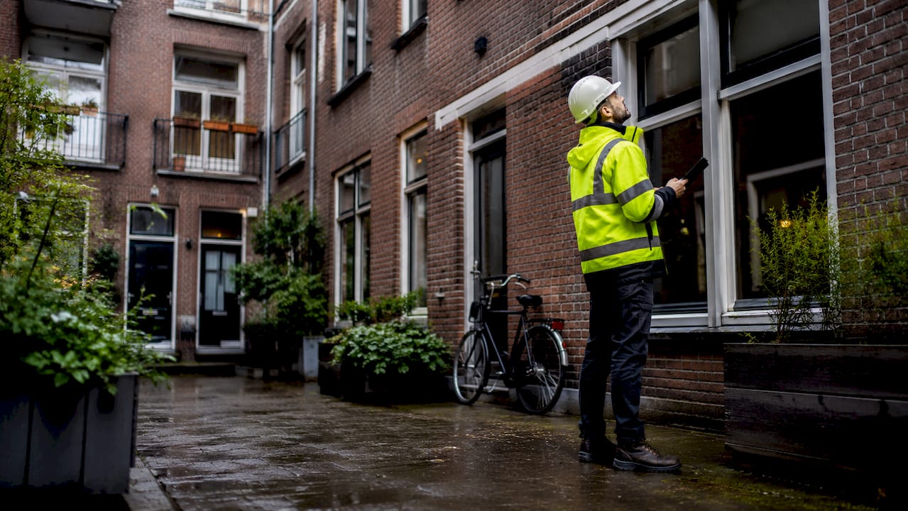 Een medewerker controleert de buitenkant van een appartementencomplex.