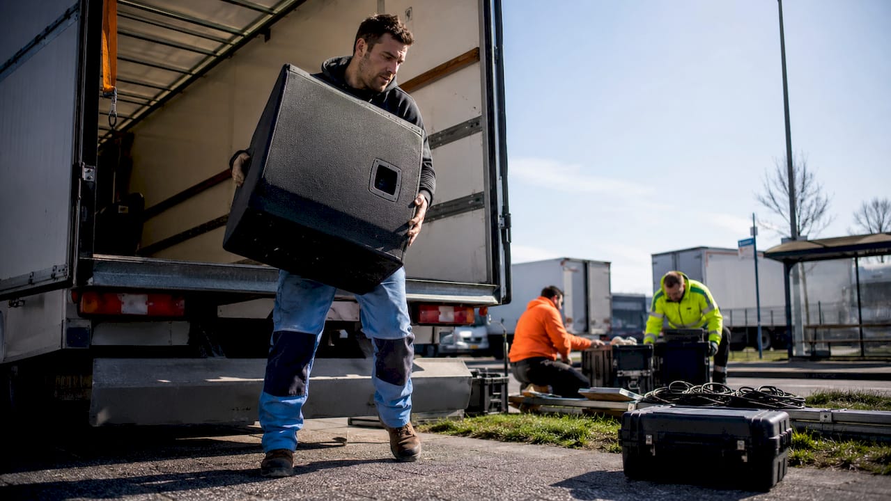 Een eventtechnicus is bezig met het uitladen van materialen uit de vrachtwagen.