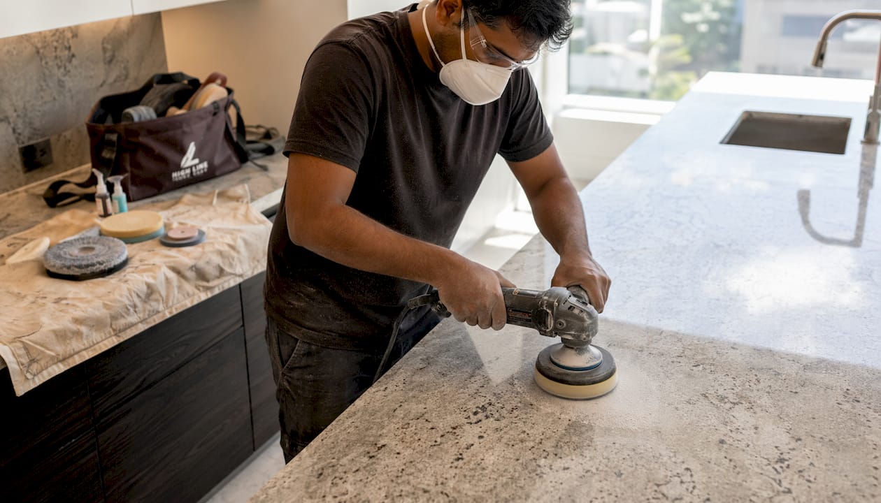 Stone restorer sanding granite countertop indoors