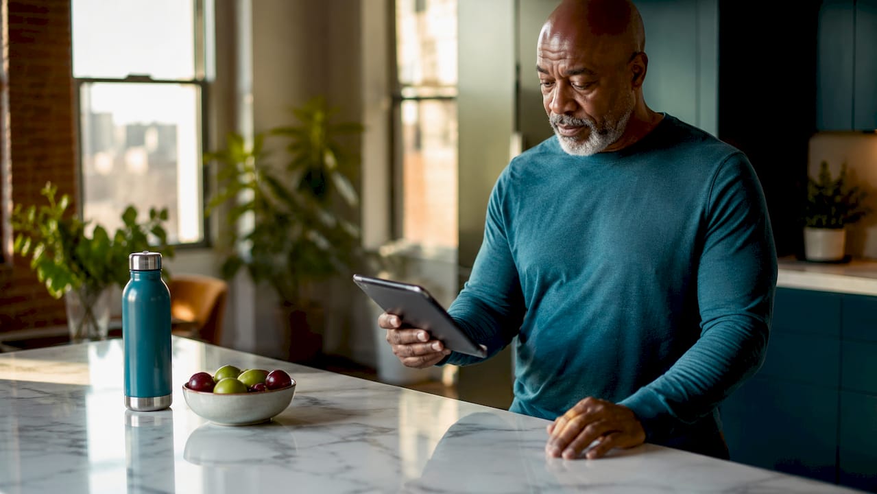 Man checking wellness metrics on tablet in home office