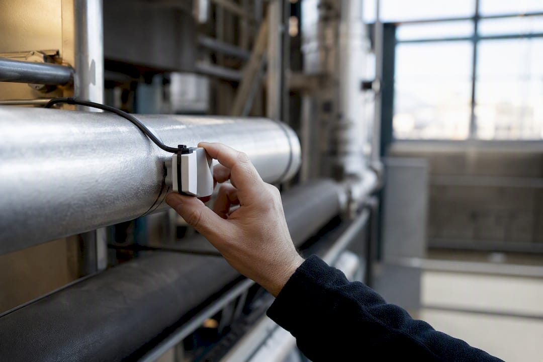 Réglage d’un capteur énergétique par un technicien dans une salle technique d’immeuble
