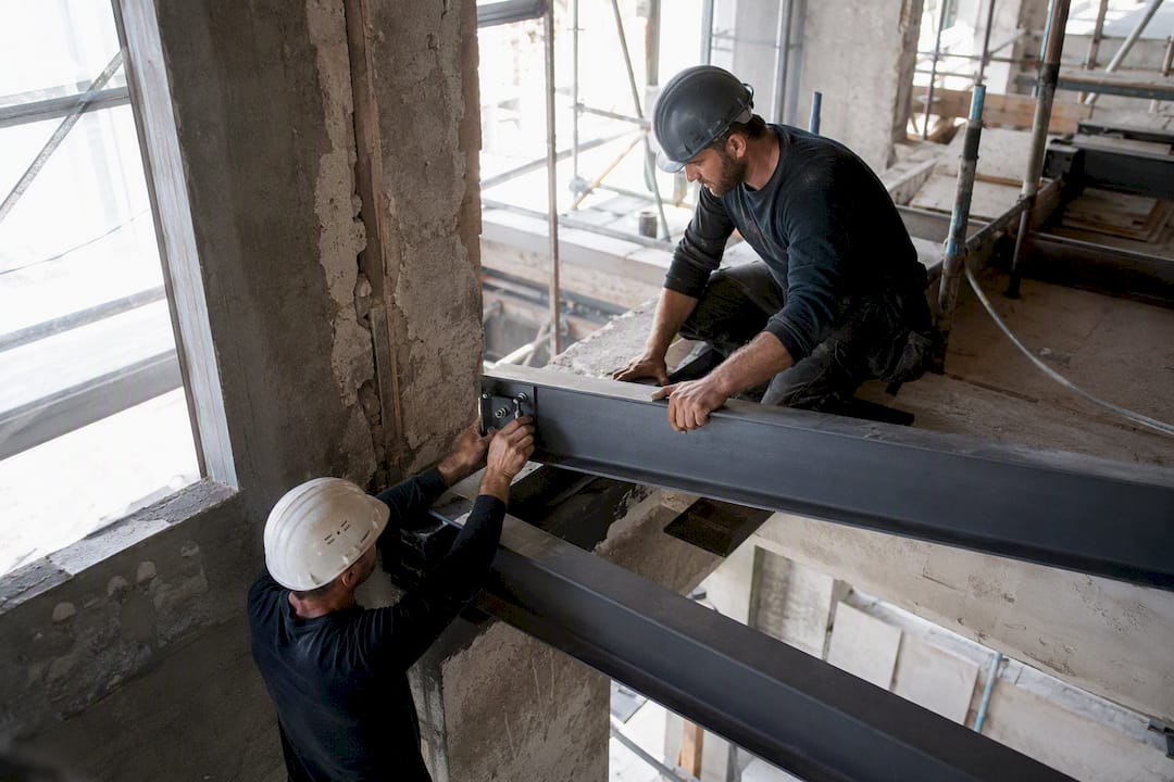 Des ouvriers posant une poutre porteuse lors de la rénovation d'un bureau