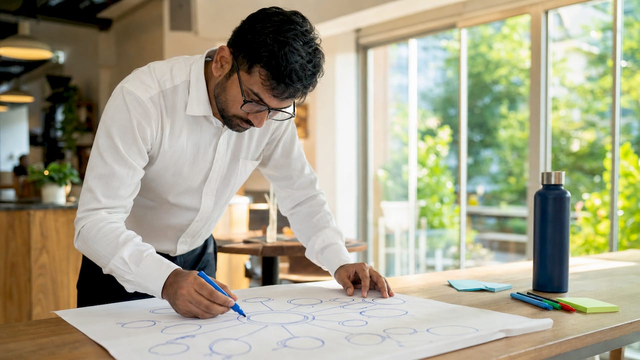Man mapping stakeholders on paper at desk