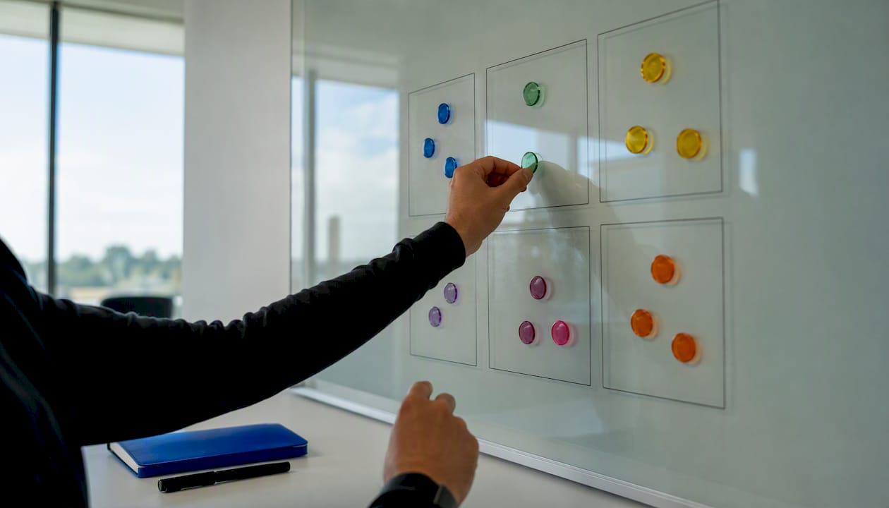 Hands placing KPI tokens on transparent board