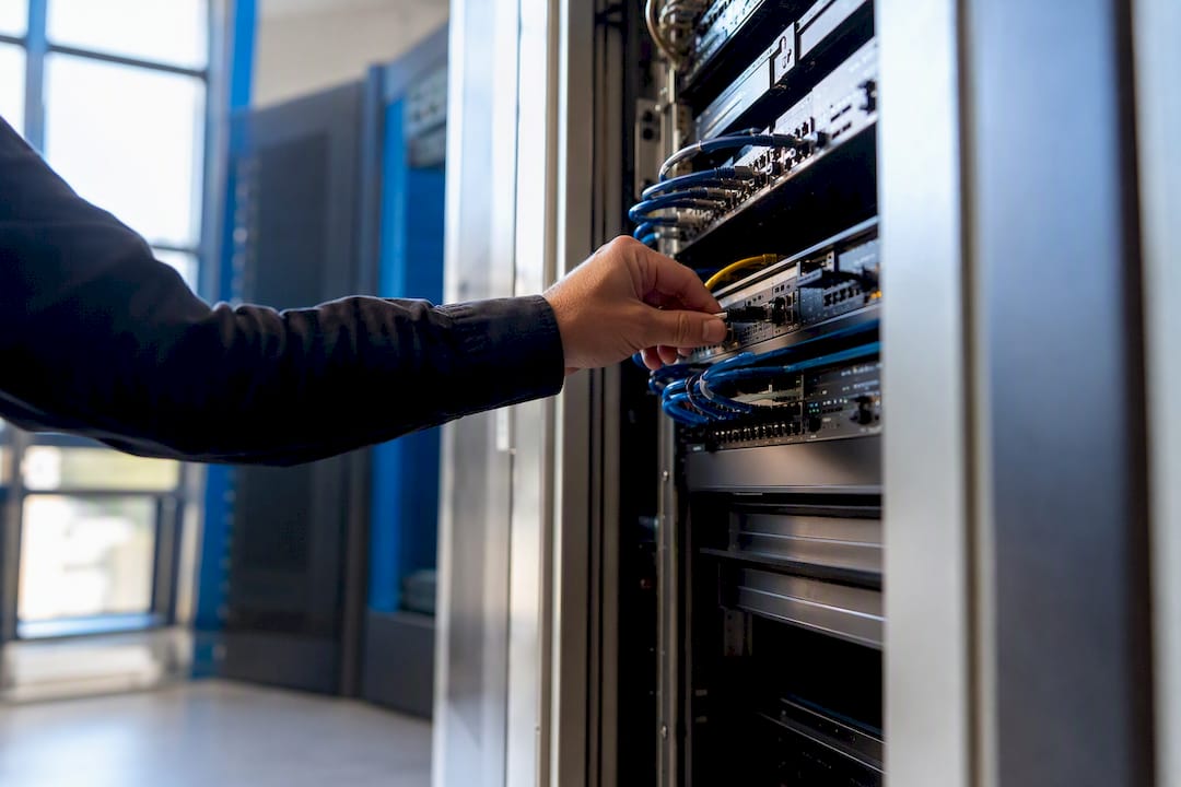 Hand connecting network cable in server rack