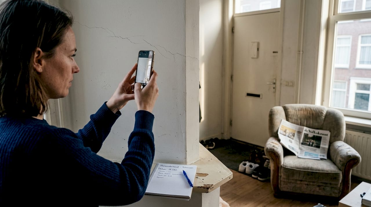 Vrouw maakt foto’s van scheuren in de muur met haar telefoon