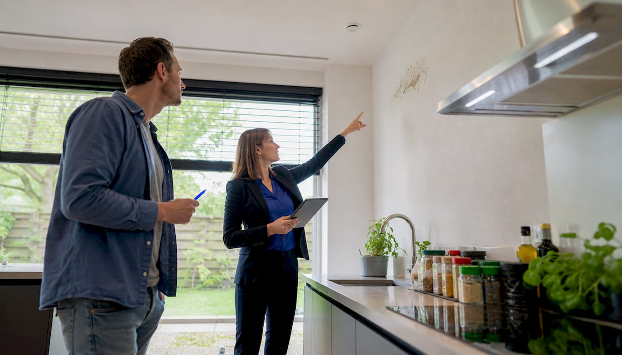 Een potentiële koper overlegt samen met de makelaar over de bouwkundige keuring van de woning.