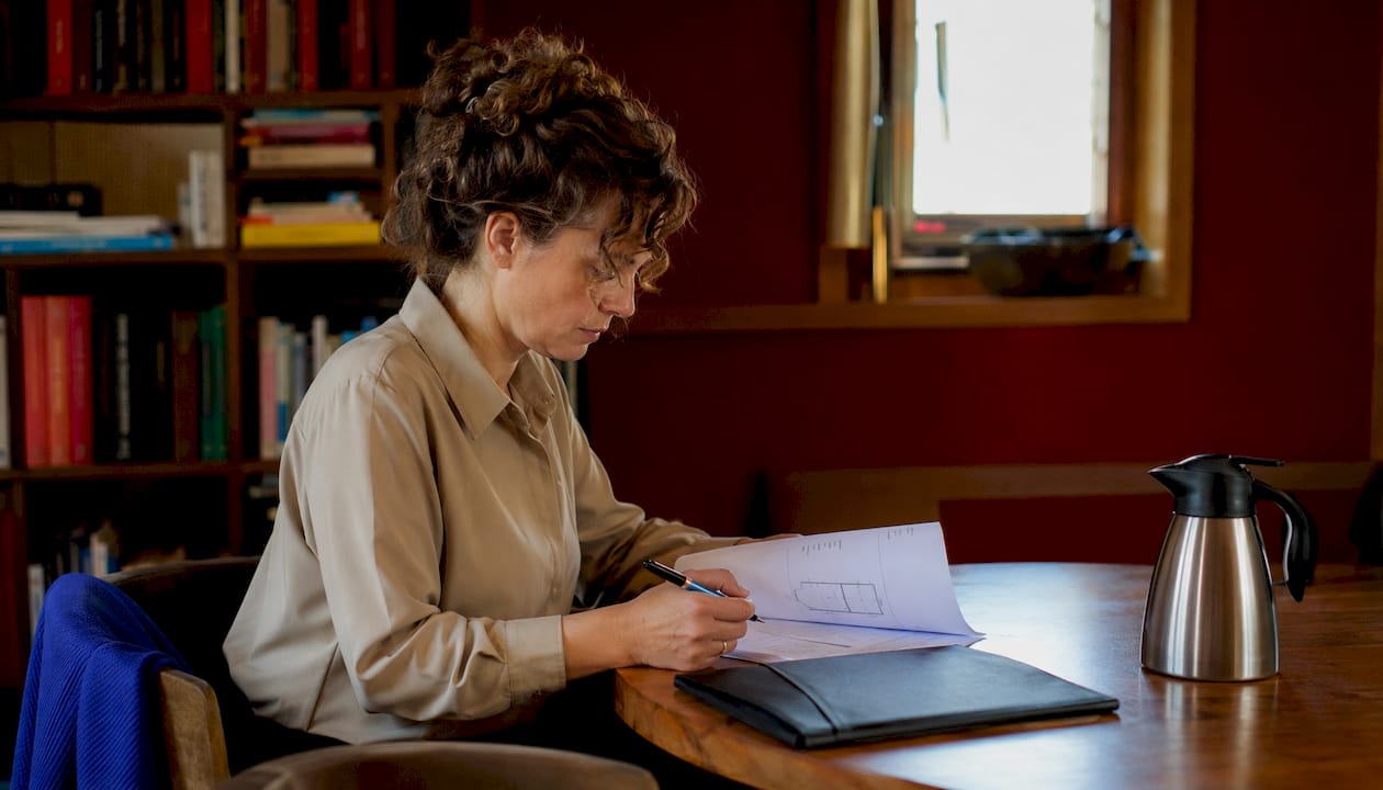 De inspecteur neemt het bouwkundig rapport rustig door aan de keukentafel.