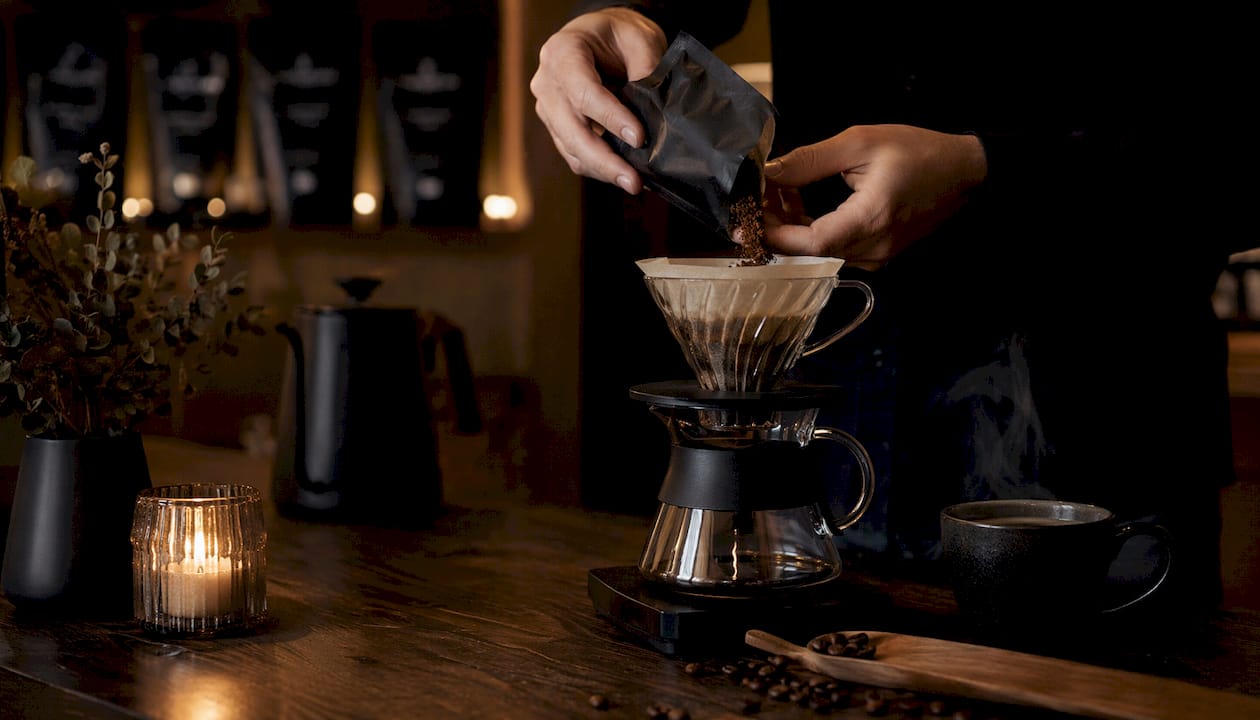 Barista z wprawą przygotowuje kolumbijską kawę, sięgając po drip V60.