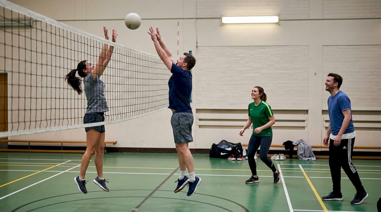Eine mannschaft trifft sich in der sporthalle zu einem entspannten volleyballmatch.