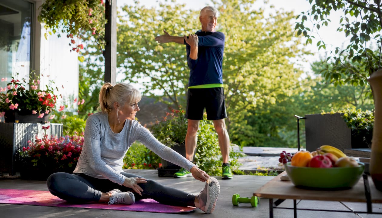 Wie Bleibe Ich Ab 50 Fit Und Gesund: Tipps Für Deinen Alltag! 1 Ein älteres ehepaar dehnt sich gemeinsam im wohnzimmer und genießt dabei die gemeinsame bewegung.