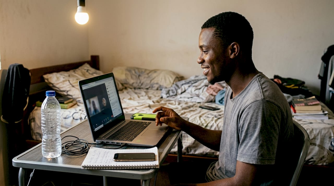 Young man debates on laptop at small desk