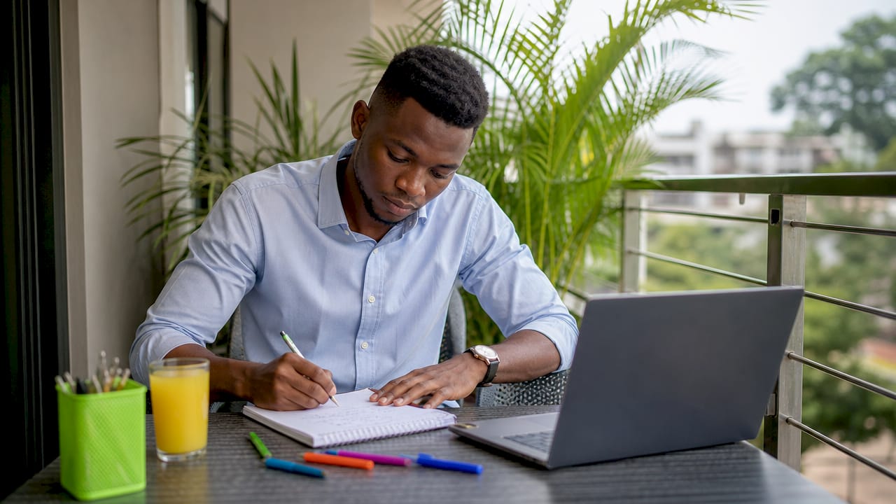 Hands of Nigerian man writing interview preparation notes
