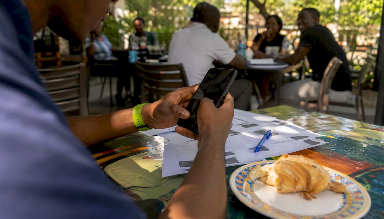 Explaining Misinformation Online: A Practical Guide 2 Hands holding smartphone and fact-check papers in café