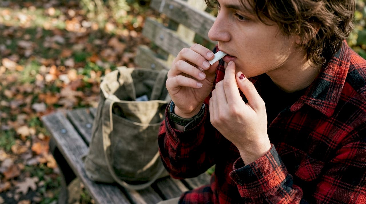 Hands using mint herbal pouch on park bench